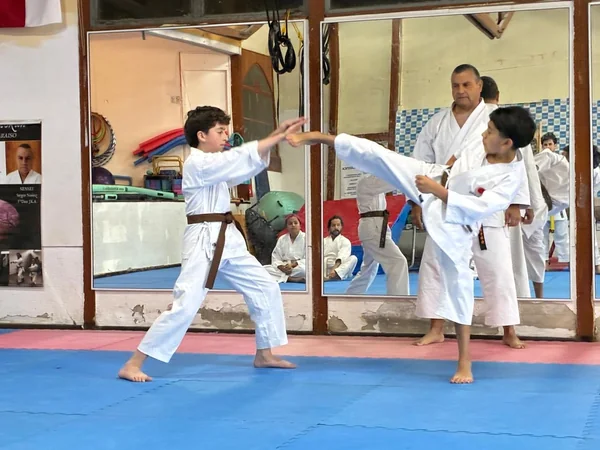 Alumnos jóvenes practican técnica en pareja con supervisión.